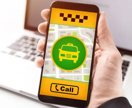 A hand holds a smartphone displaying the PerGo taxi app with a map background, a yellow car icon in a green circle, and a prominent yellow Call button at the bottom&mdash;perfect for modern transportation management software solutions.